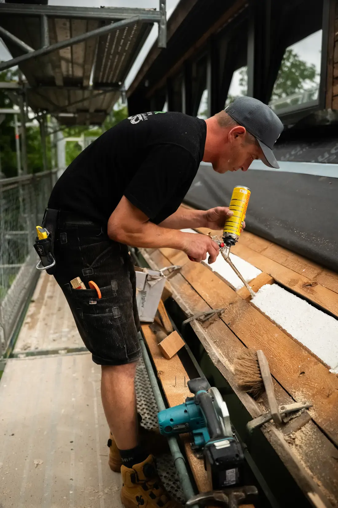 Dachdecker der Wunder Bedachungen GmbH dichtet Dämmplatten an der Traufe mit Montageschaum ab
